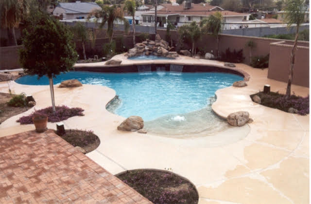 Freeform Arizona pool with natural rock waterfall and expansive desert decking