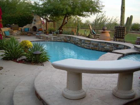 Freeform desert pool with spa, cast stone bench, and outdoor living area built by Optima Pools in Arizona