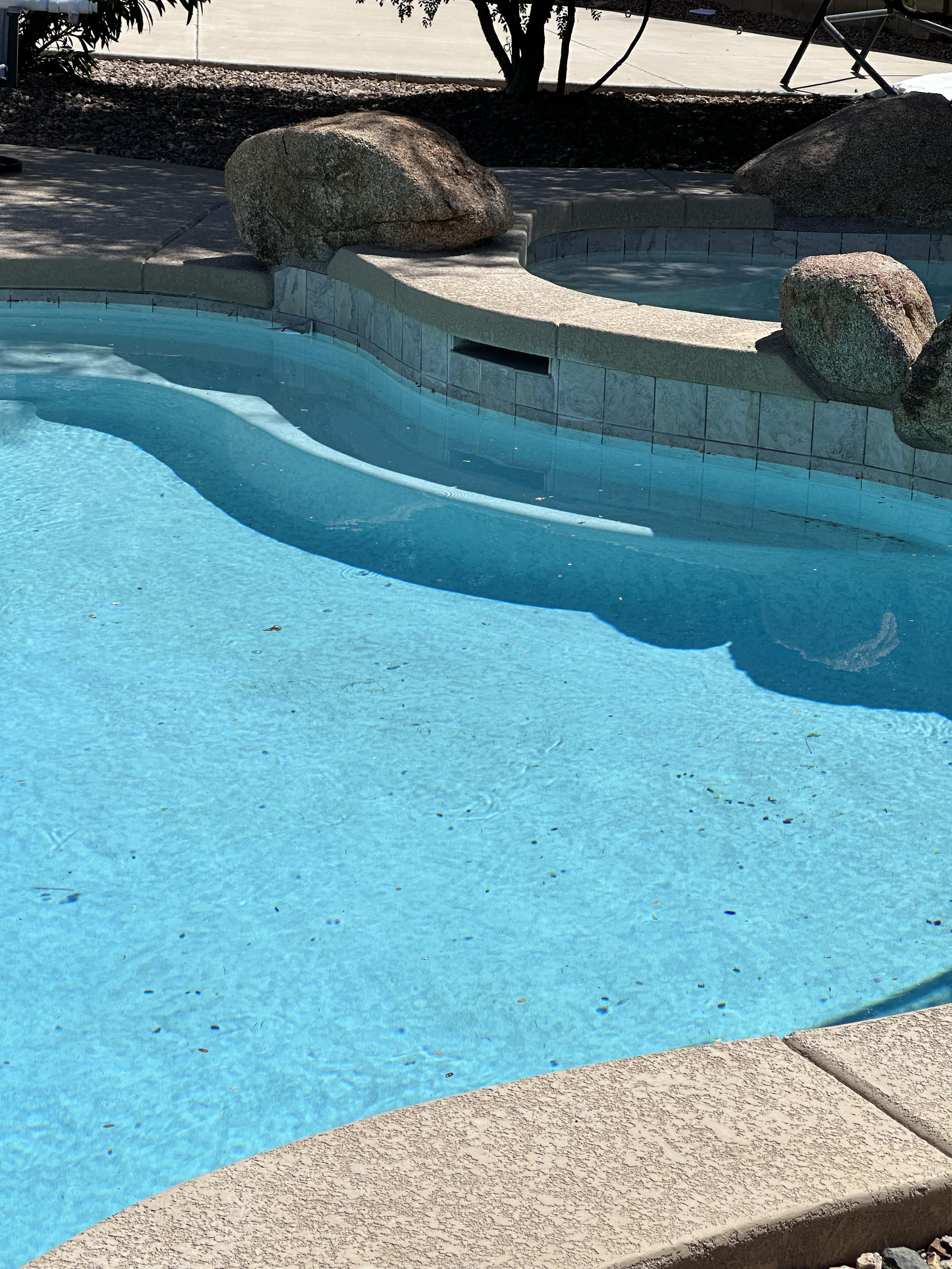 Custom pool with natural granite boulders, stone coping, and a raised spa in Arizona