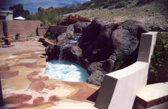 Elevated spa with cascading natural rock waterfall and flagstone decking in the Arizona desert